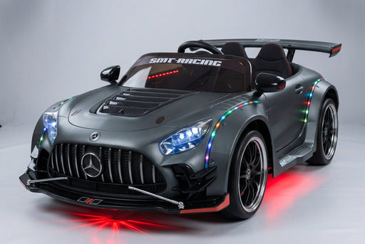 Studio view of the grey Mercedes-Benz AMG GT 24V drift ride-on car illuminated with red underglow lighting, colorful body LED accent lights, and bright blue headlights