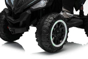 Close-up of a black children's ride-on vehicle with rugged off-road tires, a white ring accent around the wheel rims, and a glossy black body on a white studio background.
