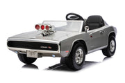 A silver toy ride-on car styled like a 1970 Dodge Charger R/T, featuring a black convertible seat, a black steering wheel, a chrome-look hood scoop with red lights, and black tires, shown on a white background.