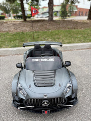 Grey Mercedes-Benz AMG GT 24V kids ride-on drift car from the front, showcasing wide body styling, headlights, and a rear wing.