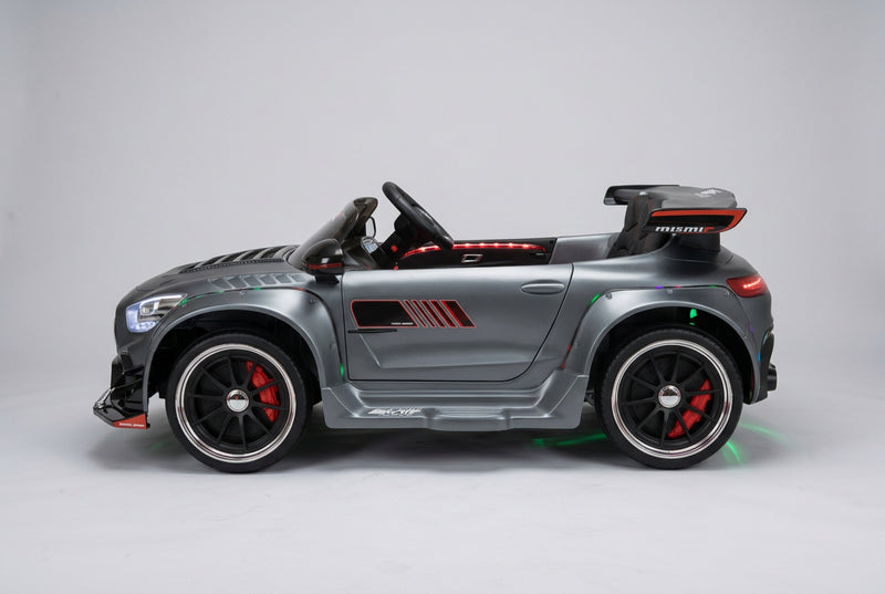 Side view of the licensed Mercedes-Benz AMG GT 24V electric ride-on car in matte grey, equipped with a wide-body kit and deep dish sport-style rims
