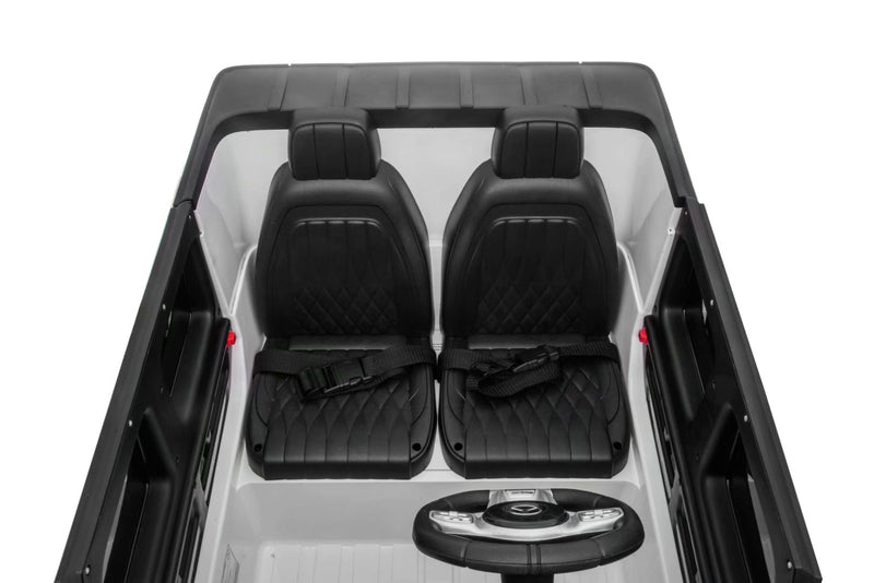 Interior of Mercedes G63 kids ride-on car showing dashboard, leather seats, seatbelts, and built-in music system.