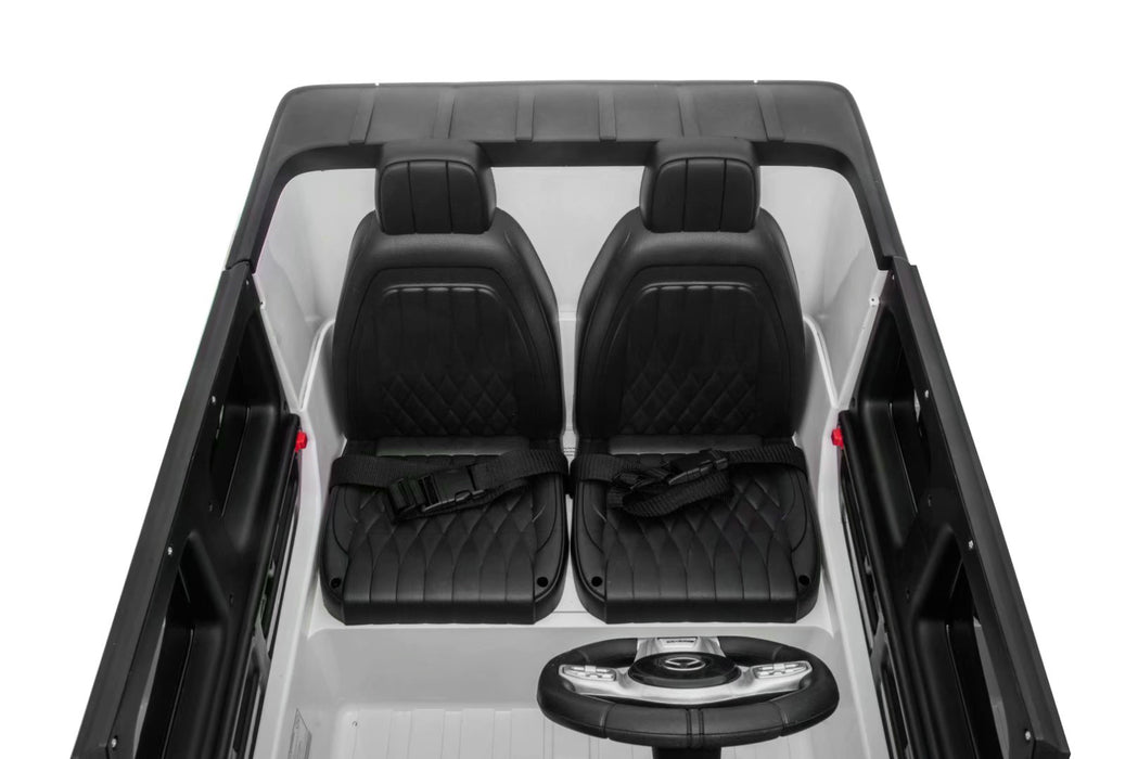 Interior of Mercedes G63 kids ride-on car showing dashboard, leather seats, seatbelts, and built-in music system.