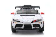A white Toyota Supra GT-R style children's ride-on toy car with black and red accents, photographed from the front on a clean white background.