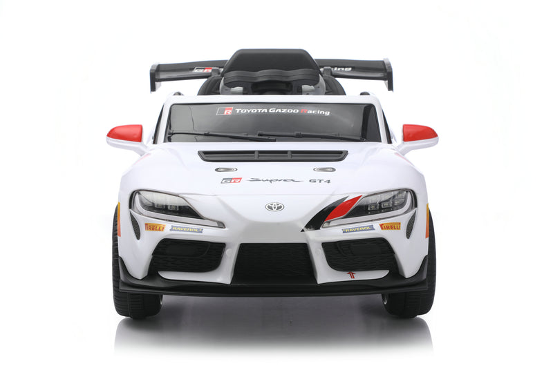 A white Toyota Supra GT-R style children's ride-on toy car with black and red accents, photographed from the front on a clean white background.