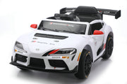 A white Toyota Supra GT-R licensed ride-on toy car with black and red racing decals, shown from a three-quarters front angle on a white studio background.
