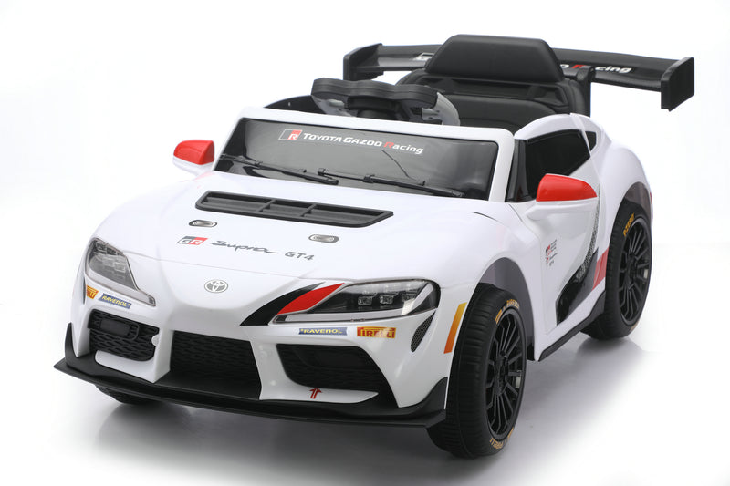 A white Toyota Supra GT-R licensed ride-on toy car with black and red racing decals, shown from a three-quarters front angle on a white studio background.