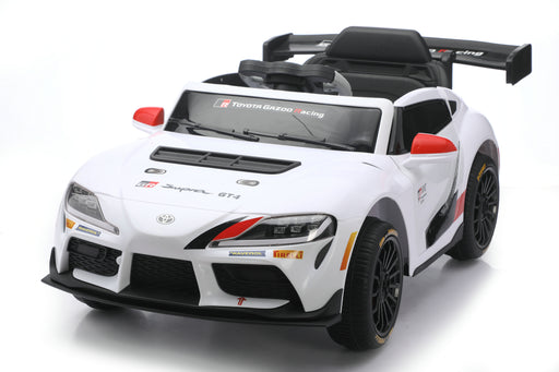 A white Toyota Supra GT-R licensed ride-on toy car with black and red racing decals, shown from a three-quarters front angle on a white studio background.