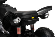 Close-up of the rear section of a black ATV or quad bike, showing the seat, rear fender, tail light, suspension shocks, and part of the tire against a white background.