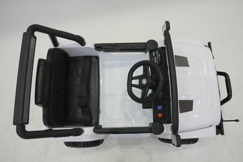 Parent using remote control with white ride-on Jeep Wrangler